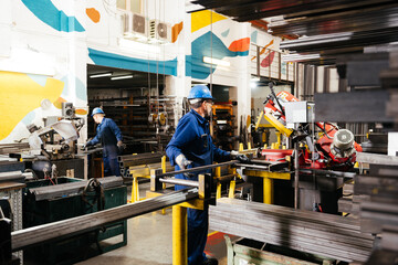 Anonymous male factory workers working in industrial metal workshop
