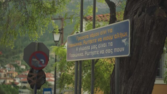Sign introducing the classic town of Leonidio Greece at entrance below old tree