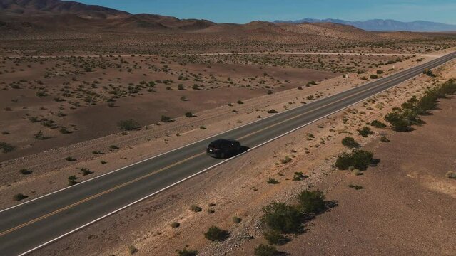 Modern car driving on desert highway in Nevada. Empty street road from above in the dry hot Wild West America landscape. Aerial drone