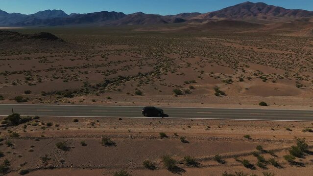 Car driving on desert highway in Nevada. Empty street road from above in the dry hot Wild West America landscape. Aerial drone