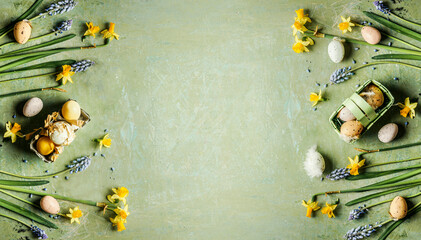 Green Easter background with springtime flowers and Easter eggs, top view. Frame - 713097138