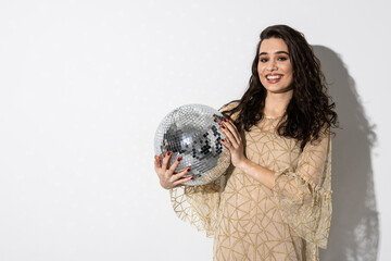 Naklejka premium Happy young woman wearing dress smiling is holding disco ball. Party concept