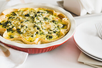 Quiche. Healthy homemade chicken pie with broccoli and spinach on white wooden table