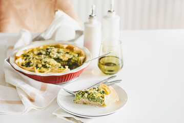 Quiche. Healthy homemade chicken pie with broccoli and spinach on white wooden table