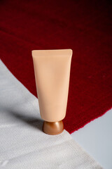 Plastic tube for cream or lotion. Skin care or sunscreen cosmetic with stylish props on red and white background 