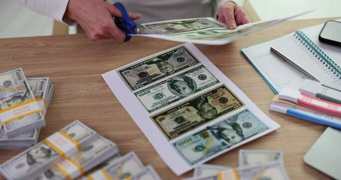 Criminal cuts dollar bills with scissors printed on printer closeup