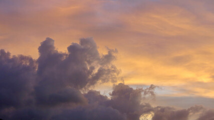 Clouds at sunset. The sky is painted with bright colors by the rays of the setting sun. The rays of the setting sun pass through the clouds.