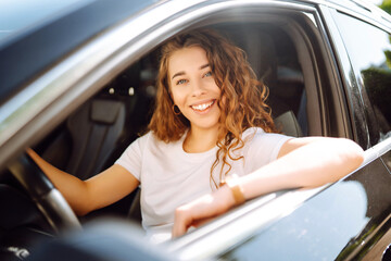 A happy woman is driving a car and smiling. Automobile travel. Sharing a car. Lifestyle concept.