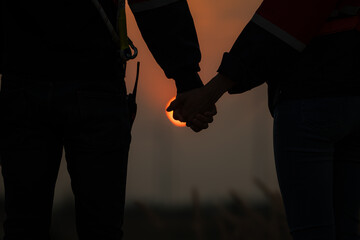 Silhouette of a man and woman holding hands on sunset background