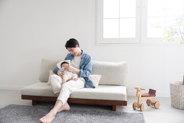 頑張って赤ちゃんを抱っこしてお世話するパパ 広角