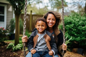 diverse mother and son on a backyard swing in summer or autumn. Mother's Day. Mom and child. Parenthood, adoption, family values.