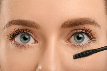 Obraz premium Woman applying mascara onto eyelashes, closeup view