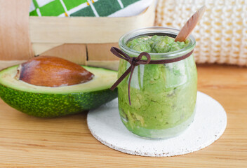 Fresh avocado puree in a small glass jar. Homemade face or hair mask, natural beauty treatment and spa recipe. Copy space.