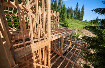 Housing structure made of wooden frames in process of construction close to forest. Start of new construction for comfortable house on mountain. Concept of contemporary architectural design.