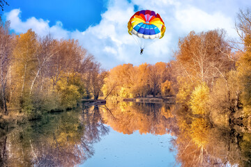 Paragliding over a river and forest on a fall sunny day.