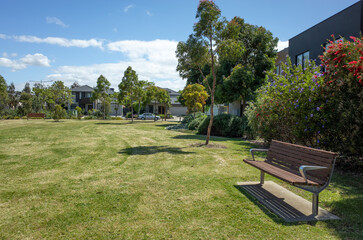 Background texture of a public suburban park with vacant grass lawn, sitting bench seats and...