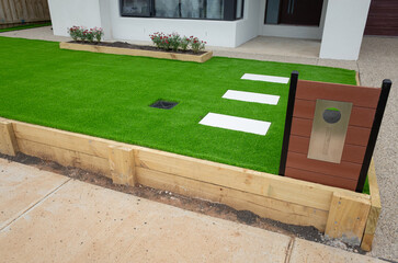 Landscaping project of artificial grass or synthetic turf with a wooden raised garden bed, stepping...