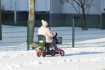 Eine ältere Person ist im Winter mit einem elektrischen Rollstuhl unterwegs 