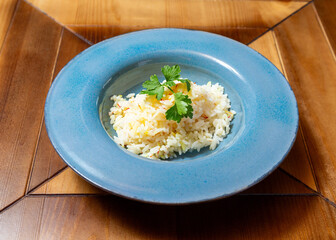 Boiled rice in a plate. On a wooden table.