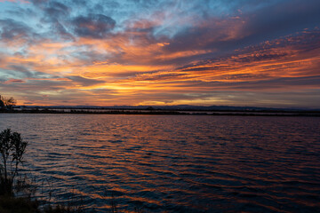 Beautiful landscape at sunset with a stunning sky in the rice fields of the Albufera Natural Park with the orange reflections of the sky on the water of the rice fields, in Valencia, Spain, Europe