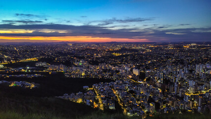 Naklejka premium Dusk on top of a mountain in the highest part of the city of Belo Horizonte in Brazil. Sunset and city lights slowly turning on.