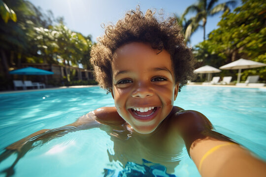 Happy little African American boy taking selfie in an outdoor swimming pool