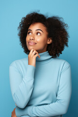Cute African American lady thinking about her inspiration touch chin looking mockup choosing product option isolated on blue color background