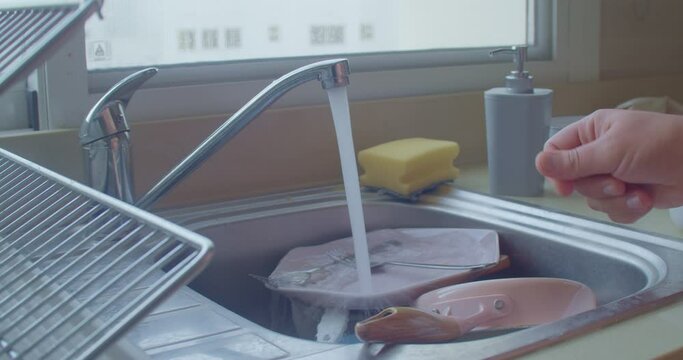 Male hand taking sponge and putting detergent on it to start washing dishes