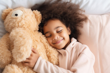 Obraz na płótnie Canvas Top view of cute little preschooler African American girl lying cuddling with favorite fluffy toy waking up in cozy home bed