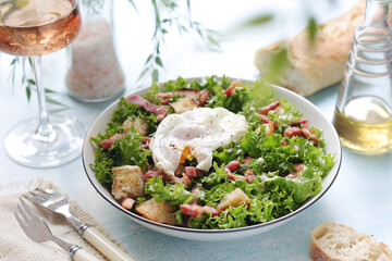 A bowl with salad lyonnaise served for lunch