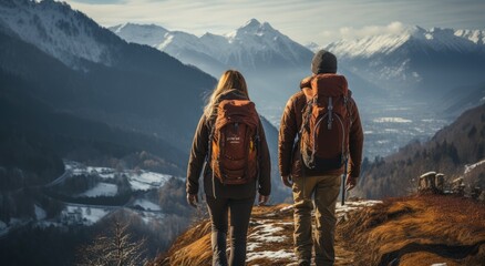 Two mountaineers brave the harsh winter elements as they stand atop a snow-covered summit, their jackets and backpacks signaling their love for the outdoors and determination to conquer the mountain  - obrazy, fototapety, plakaty