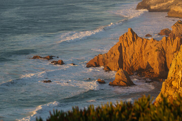 Golden illuminated rocks during sunset at atlantic ocean coast on westernmost point, Cape Roca,...
