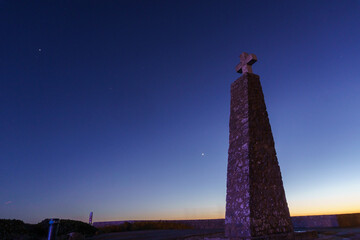 Cross on a stone pillar at Cabo da Roca under the night sky with planets Venus, Saturn and Jupiter...