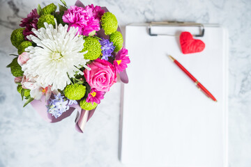 blank paper clipboard,pen, daisy and roses bouquet. Elegant, Beauty blog composition.Valentine's Day,Mother's Day concept. selective focus.Greeting card for spring holiday