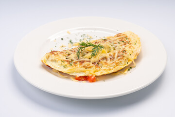 Breakfast. Omelet with vegetables and cheese on a white plate and a white background.