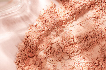 Loose powder for makeup in a natural beige color. Powder texture, cosmetic peach background with copy space.