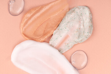 Different smears and drops of cream on a beige background. Skin care cosmetics cream, scrub, powder. Cream textured cosmetic background.