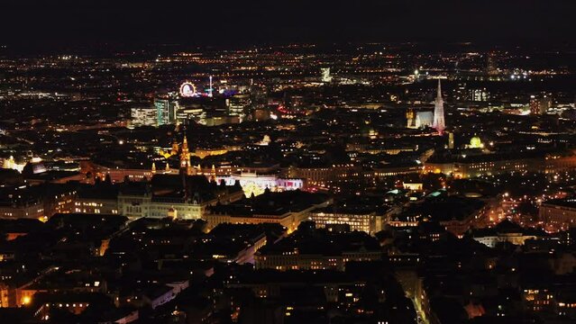 Aerial slide and pan footage of illuminated sights in city center. Rathaus, Burgtheater, Hofburg and Domkirche St Stephan. Vienna, Austria