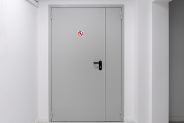 This image shows a closed white door in a contemporary building with a clear no entry sign affixed near its handle, indicating restricted access.