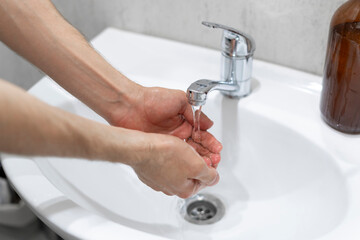A close-up image capturing the act of handwashing, with a focus on hands scrubbing together under a...