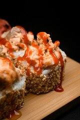 Focus on one sushi roll with sesame, toppings and hot spicy sauce