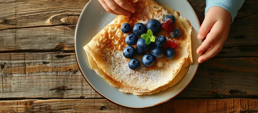 Child s hands holding pancake crepe over plate with toppings. Copy space image. Place for adding text