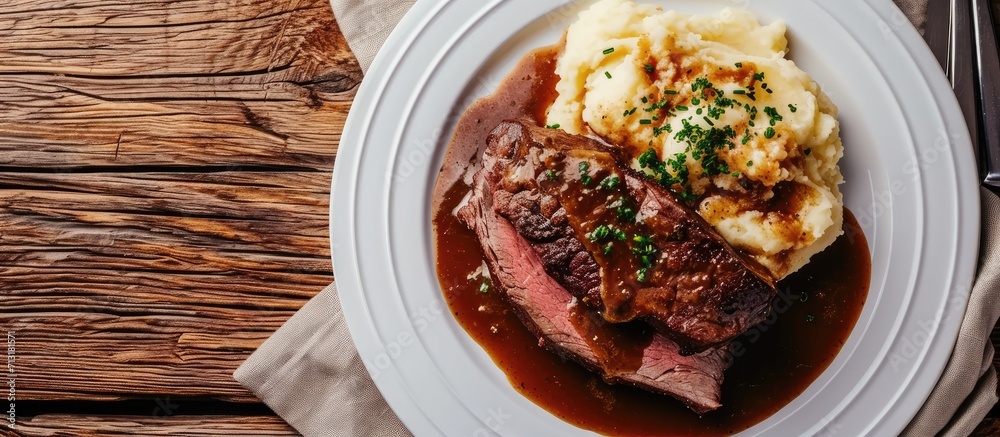 Wall mural Roast beef smothered in demi glace gravy with mashed potatoes on white plate Top view. Copy space image. Place for adding text