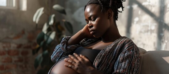 Young pregnant black woman suffering from headache or migraine feeling sick sitting on sofa at home free space Sad african american expecting lady touching her forehead and big tummy home alone - obrazy, fototapety, plakaty