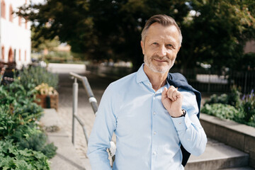 Successful Modern Bestager Businessman, Relaxed in the Park with Jacket Draped over Shoulder,...