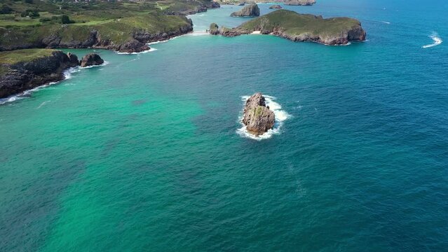 Aerial perspective of beautiful and famous Green Coast of Spain. Typically Asturian landscape with high cliffs, turquoise water, small islands. Drone going backwards, ascending. Peaceful landscape