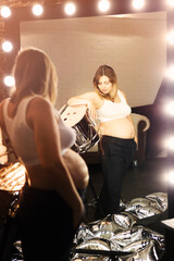 Young pregnant woman posing near the mirror