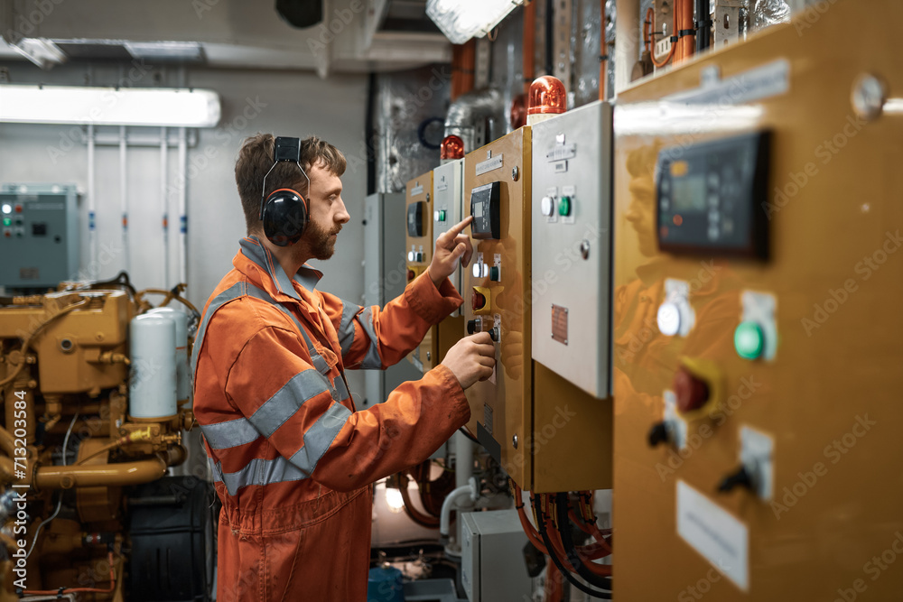 Wall mural young engineer officer starting diesel generator manually in engine room.