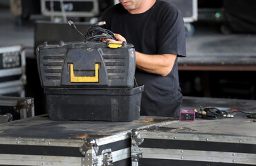 Technician preparing the lighting wiring for a musical show on stage. Worker with toolbox working...