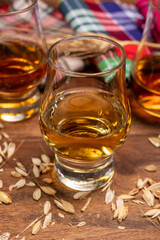 Tasting of different Scotch whiskies strong alcoholic drinks, drum of whiskey and colorful Scotch tartan on background close up